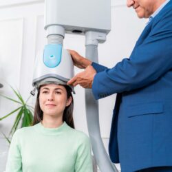 woman in a chair receiving tms treatment by a male emloyee